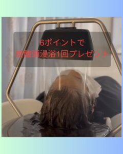 Person lying with head submerged in a carbonated head bath under a spa hood, with a semi-transparent Japanese promo banner across the scene.