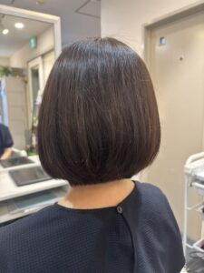 Back view of a person with a smooth dark brown bob haircut in a hair salon.